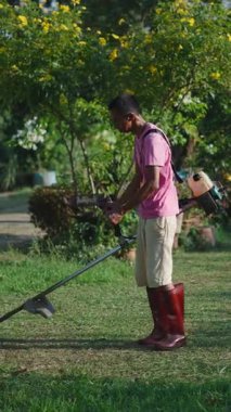 Bahçe bakımı yapan bir fırça kesici kullanan profesyonel bahçıvan - FullHD Dikey