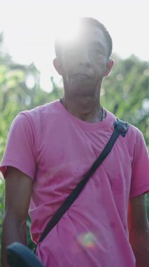 Bahçıvan elinde fırça makasıyla doğadaki kameraya bakıyor.