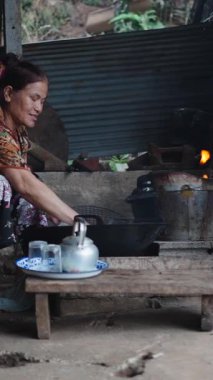 Geleneksel Taylandlı kadın geleneksel ev yapımı çay hazırlıyor köy mutfağında odun ateşinin üzerinde - FullHD dikey