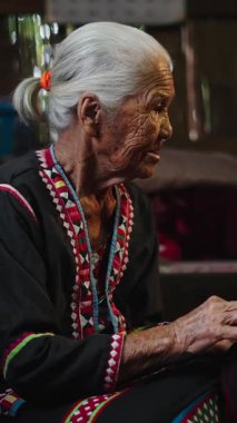 Yaşlı bir Asyalı zanaatkar, bronzlaşmış elleri FullHD Dikey Tekstil üzerinde titizlikle çalışır.