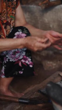 Yaşlı Vietnamlı bir kadın alevleri yanık tutmak için yanan küçük bir ocağa odun parçaları ekliyor.