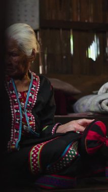 Geleneksel giysiler içinde Taylandlı kadınlar mütevazı bir ahşap kulübede dikiş dikiyorlar.