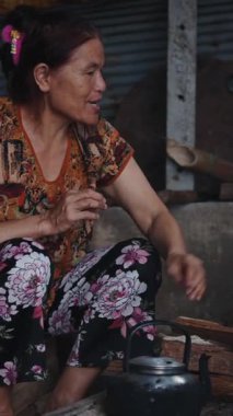 Vietnamlı bir kadın geleneksel ahşap sobayı kullanarak sıcak bir içecek hazırlıyor.