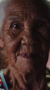 Kameraya bakan buruşuk derili, geleneksel Taylandlı yaşlı bir kadının portresi.