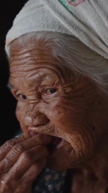 Az dişli yaşlı kadın mütevazı bir ortamda taze çilek çiğner - FullHD Dikey