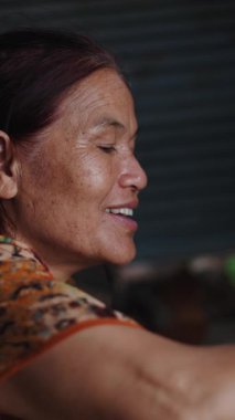 Mutlu ve gülümseyen bir Asyalı kadının portresi geleneksel yemekleri mütevazı bir kulübede hazırlıyor.