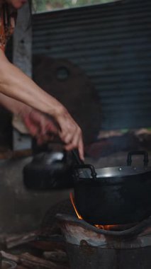 Asyalı bir kadın, köy mutfağında ev yapımı geleneksel ahşap ateşiyle ev yapımı yemekleri basit bir ortamda, FullHD dikey