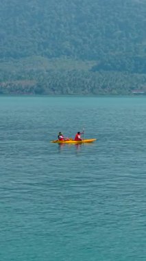 DollHD dikey adaların yakınındaki sakin bir denizde kano süren iki adam.