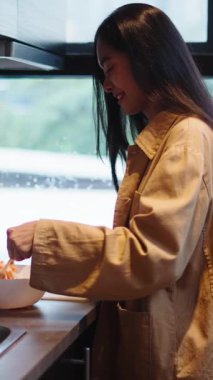 Genç bir kadın besleyici bir yemek hazırlıyor dikkatle bir kaseye taze malzemeleri karıştırıyor - FullHD Dikey