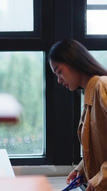 İçi önceden pişirilmiş yiyeceklerle dolu plastik bir paketi açmak için makası eline alan genç bir kız.