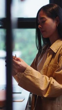 Asyalı bir kadın mutfak penceresinin yanında dikey dururken lezzetli geleneksel bir yemeğin tadını çıkarıyor.