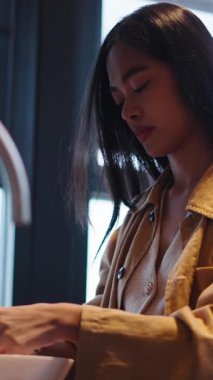 Genç bir kadın büyük pencereli, parlak bir mutfakta sağlıklı bir yemek hazırlıyor.