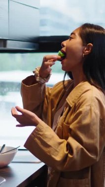 Genç bayan besleyici bir yemek hazırlıyor ve büyük bir memnuniyet ve mutlulukla tadıyor - FullHD Dikey