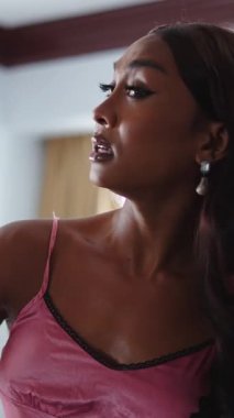 Otel odasında makyajlı ve saçını tarayan genç trans kadın FullHD Dikey