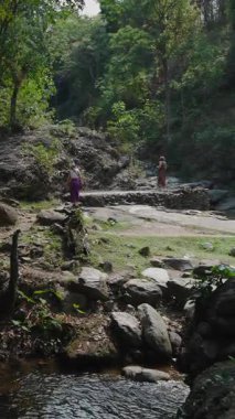 Yürüyüşçüler parlak güneş ışığı altında dağ yolunda yürüyor.