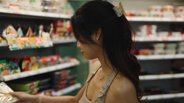 Süpermarket rafından alışveriş yaparken beslenme etiketini kontrol eden kişi