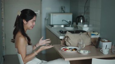 Pürüzsüz bir mutfakta sabah yemeğinin tadını çıkarırken genç profesyonel video sohbeti.