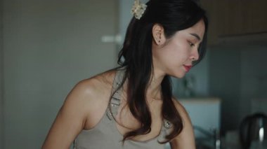 Asyalı kadın modern mutfağında bir bardak su içiyor.