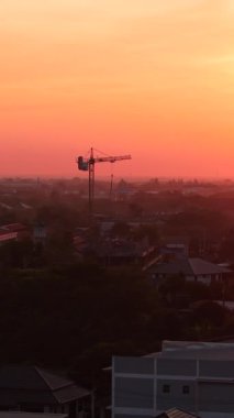 Chonburi vilayeti üzerinde ılık turuncu gün doğumu, Tayland, çatılar ve inşaat vinçleri - FullHD Dikey