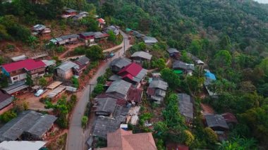 Güneydoğu Asya 'da yemyeşil bir arazide kırmızı çatılı evler barındıran dağ köyü.