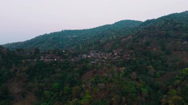 Bereketli yeşil bir dağ yamacının ortasına kurulmuş sakin bir köy, alacakaranlığın yumuşak ışığıyla yıkanmış.