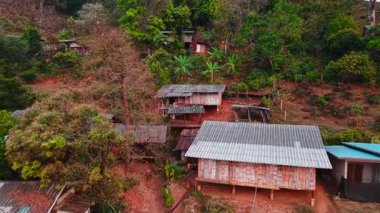 Yeşillik yamaçlarda yuva yapan ahşap evler, kırsal alanların gelişimini betimliyor.