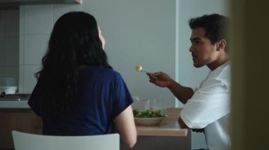 Genç çift, modern mutfaklarında birlikte sağlıklı bir yemek yiyor, yemek ve sohbet paylaşıyorlar - 4K Yatay