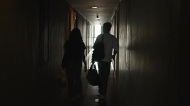 Genç çift birlikte otel koridorunda yürüyorlar ışığa doğru - 4K Yatay