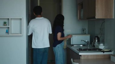 Genç çift alışveriş yaptıktan sonra erzak paketlerini modern mutfaklarına boşaltıyor - 4K Yatay