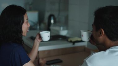 Çift dinleniyor, sıcak çayı güneşli mutfakta paylaşıyor, yakından bağlanıyor - 4K Yatay