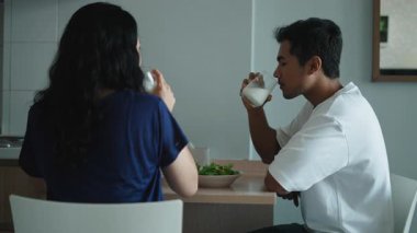 Genç çift besleyici yemeğin tadını çıkarıyor, sütü lüks mutfak tezgahında paylaşıyorlar - 4K Yatay