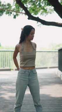 Çağdaş bir koreografi sergileyen kadın dansçı ağaçlı kentsel patika, yakınlarda metal korkuluklar...