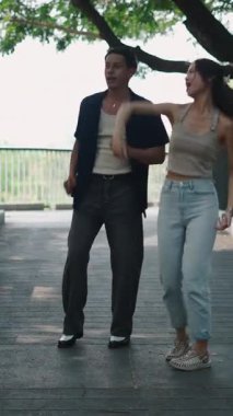 Genç çift parkta dans etmekten zevk alıyor, neşeli hareketlerini ve bağlantılarını sergiliyorlar.