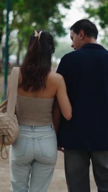 Gün batımında birlikte yürüyen çift, manzara parkı yolunda el ele tutuşuyorlar.