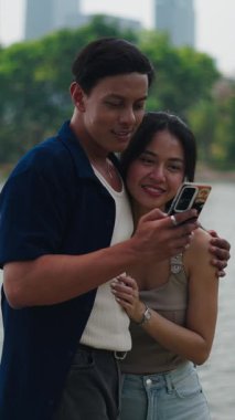 Çift samimi bir anı paylaşıyor, göl kenarındaki akıllı telefona bakıyor.