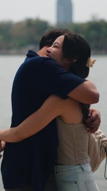 Sevgili eşler, sakin göl kenarlarında kucaklaşırlar.