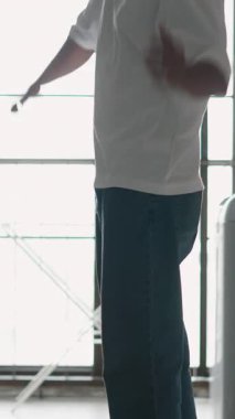 Minimalist kentsel çatı katında geniş pencerelerin yanında kareografiyi mükemmelleştiren canlı dansçı.