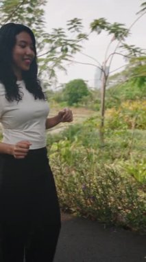 Tasasız genç kadın parkta yürürken dans ediyor - 4K Yatay