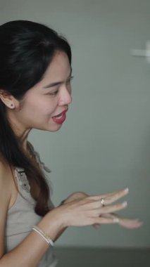 Genç bir kadın elleriyle jest yapıyor ve sağlam beyaz bir arkaplanda konuşuyor.