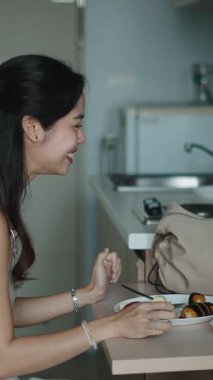 Neşeli kadın mutfak tezgahının yanında sabah yemeğinin tadını çıkarıyor.