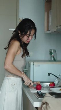 Sabah hazırlıkları sırasında mutfak tezgahının yanında taze elma kesen bir kadın.