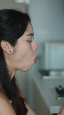 Gülümseyen kadın. Parlak tezgahın yanında kahvesini yudumluyor.