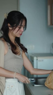 Asyalı kadın, modern ve minimalist mutfağında erzak paketlerini açıyor.