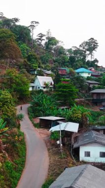 Geleneksel ahşap evleri yeşil manzaranın arasına tünemiş, mimari mirası ve huzurlu kırsal düzeni ön plana çıkaran Thai köyü yamacı.