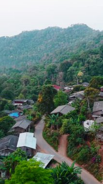 Dağ köyü, yemyeşil orman manzarası ve ahşap evler arasında yuva yapıyor.