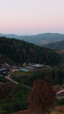Dağ köyü tepelerin arasına kurulmuş, yumuşak ışık kırsal bölgelerde altın saat boyunca sıcak bir parıltı yayıyor.
