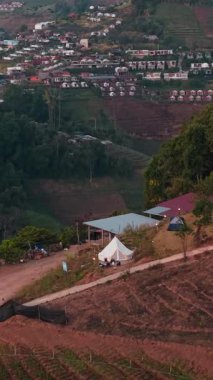 Dağ köyü kampçıları altın gün batımı ışığı altında dinleniyor, sakin bir vahşi doğa manzarası yaşıyorlar.