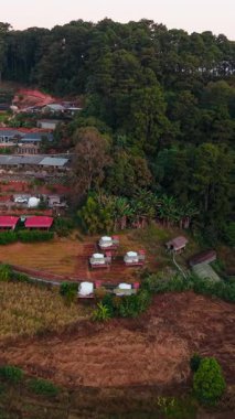 Huzurlu glamping kubbeleri, yamaçtaki bir köyün yakınlarındaki yemyeşil bir orman manzarasının ortasında huzurlu bir kaçış sunuyor.