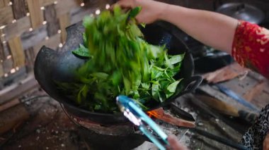 Traditional tea production process involving the careful drying of green tea leaves in a hot wok on the fire - 4K Horizontal