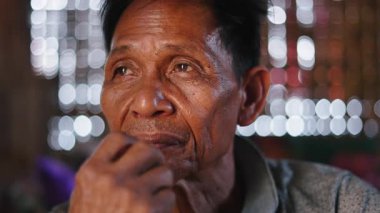 Close-up of a calm and relaxed Southeast Asian man smoking a craft cigarette exhaling smoke - 4K Horizontal